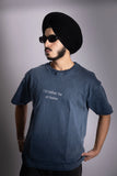 A man wearing stonewash blue oversized T-shirt with embroided text in front.