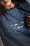 A woman wearing stonewash blue oversized T-shirt with embroided text in front.