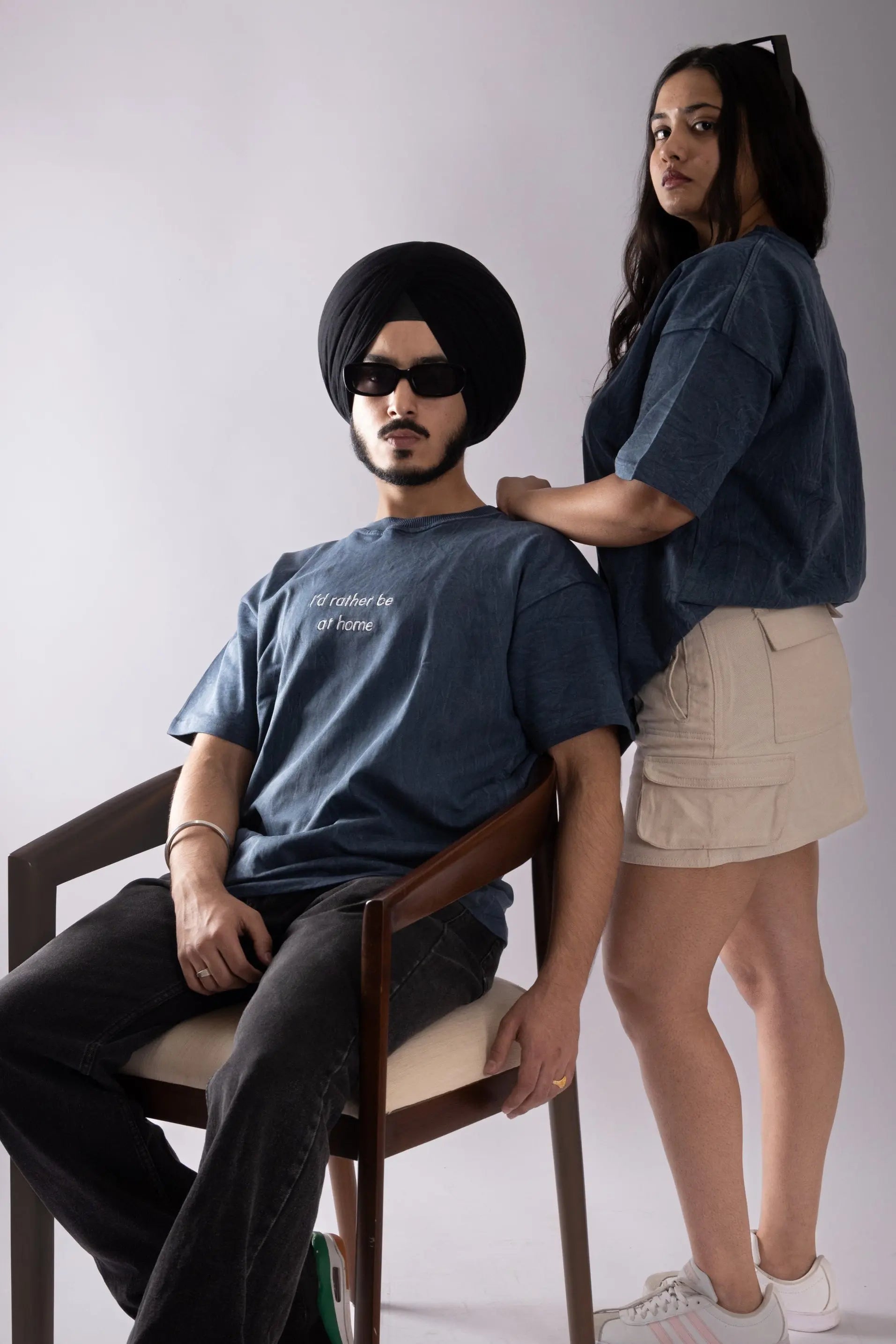 Models posing wearing stonewash blue oversized T-shirt with embroided text in front.