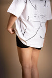 A woman wearing white oversized T-shirt showing the screen print back.