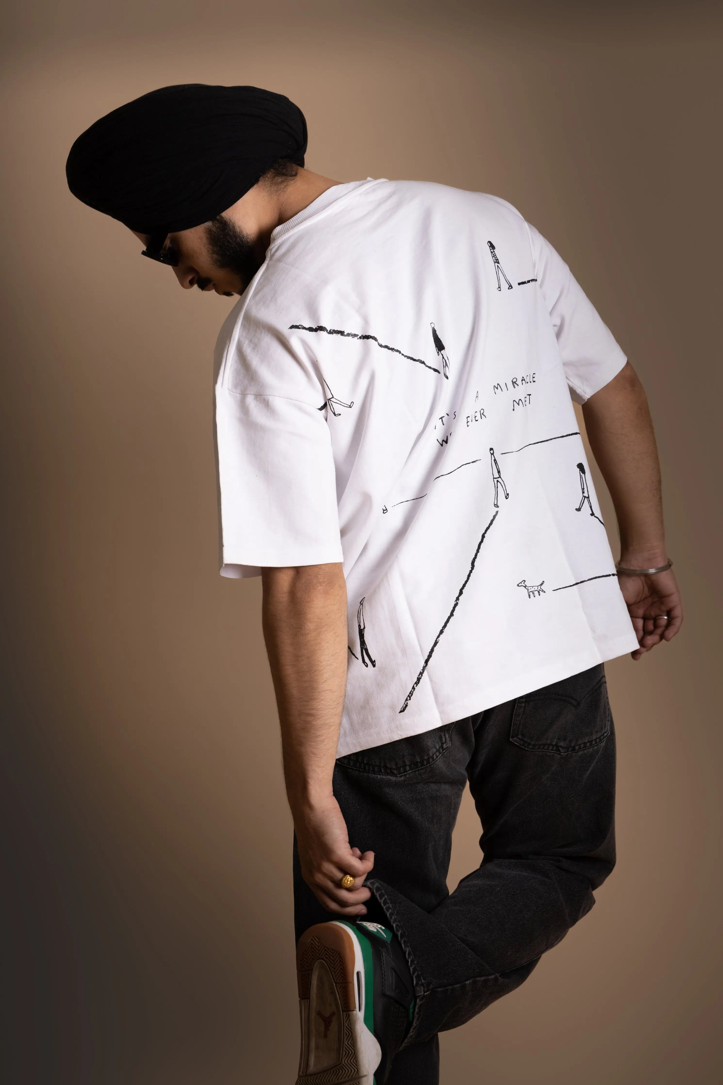 A man wearing white oversized T-shirt showing the screen print back.