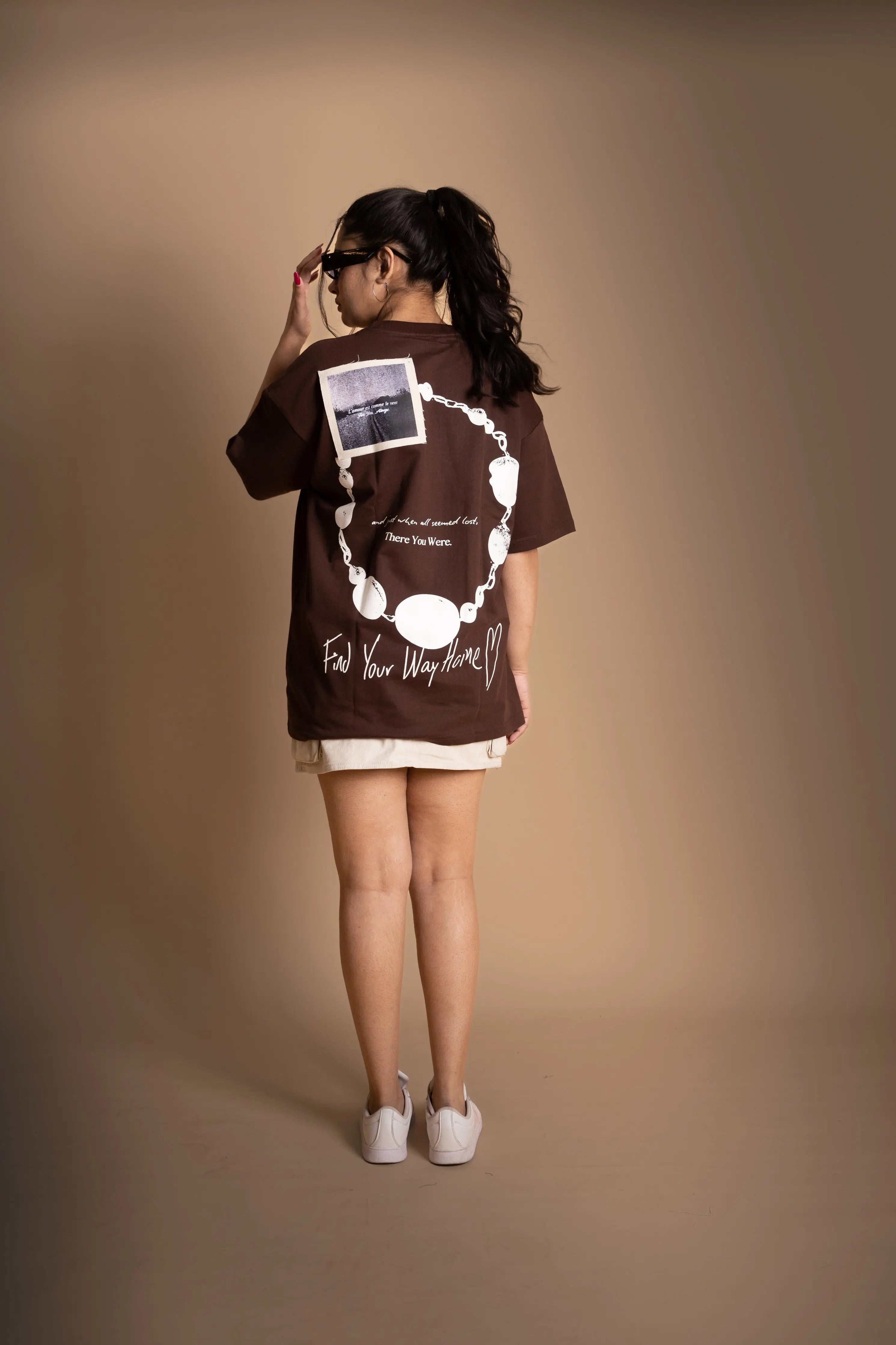 A woman wearing brown oversized T-shirt showing the back print.