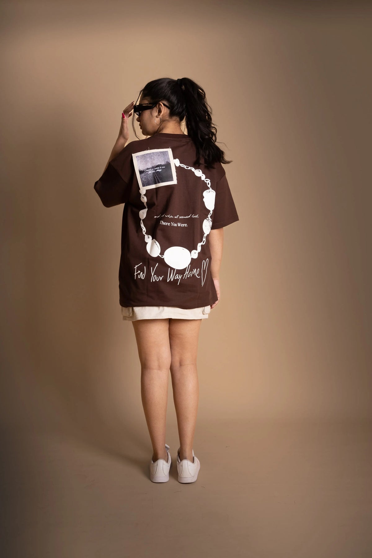 A woman wearing brown oversized T-shirt showing the back print.