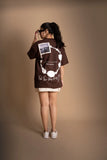 A woman wearing brown oversized T-shirt showing the back print.